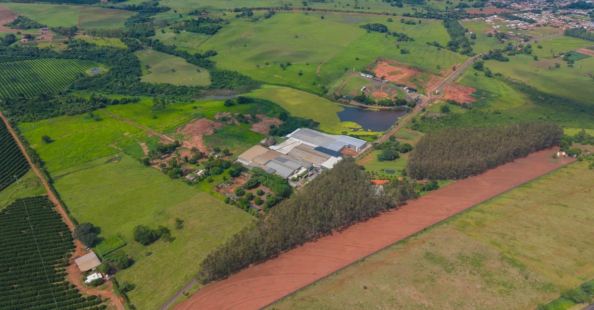 An aerial view of a large farm plot with different green fields and buildings scattered across a large property. An aerial view of a large farm plot with different green fields and buildings scattered across a large property.